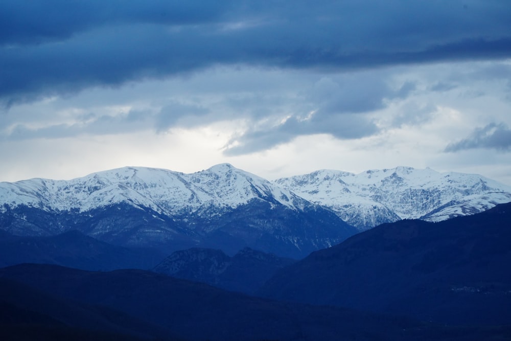 a snowy mountain range under a cloudy sky