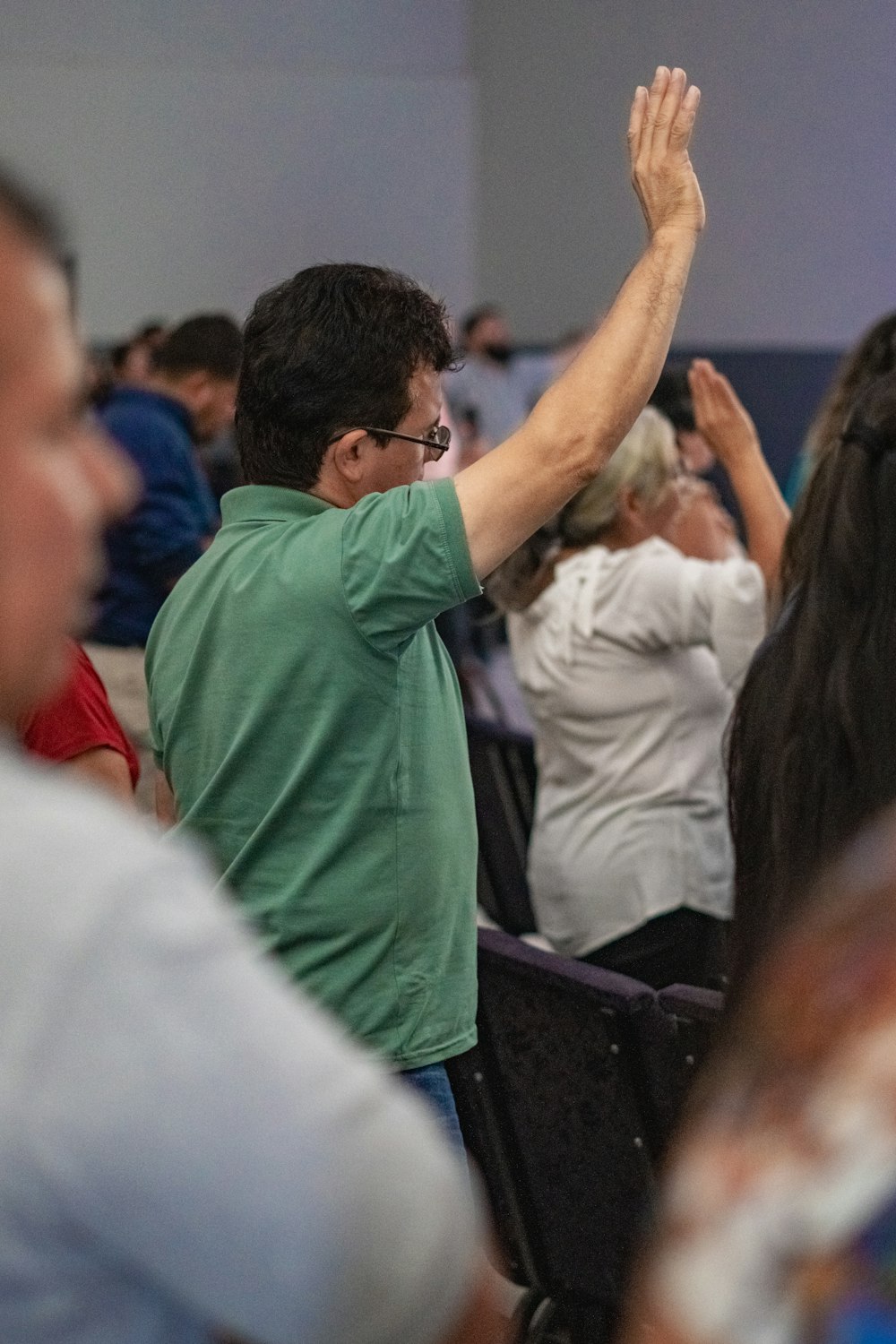 a group of people sitting in a room with their hands up