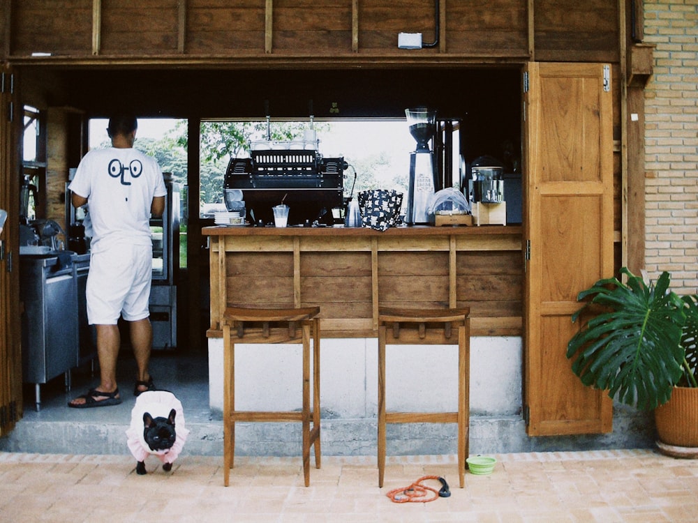 a man standing in front of a bar with a dog on the floor