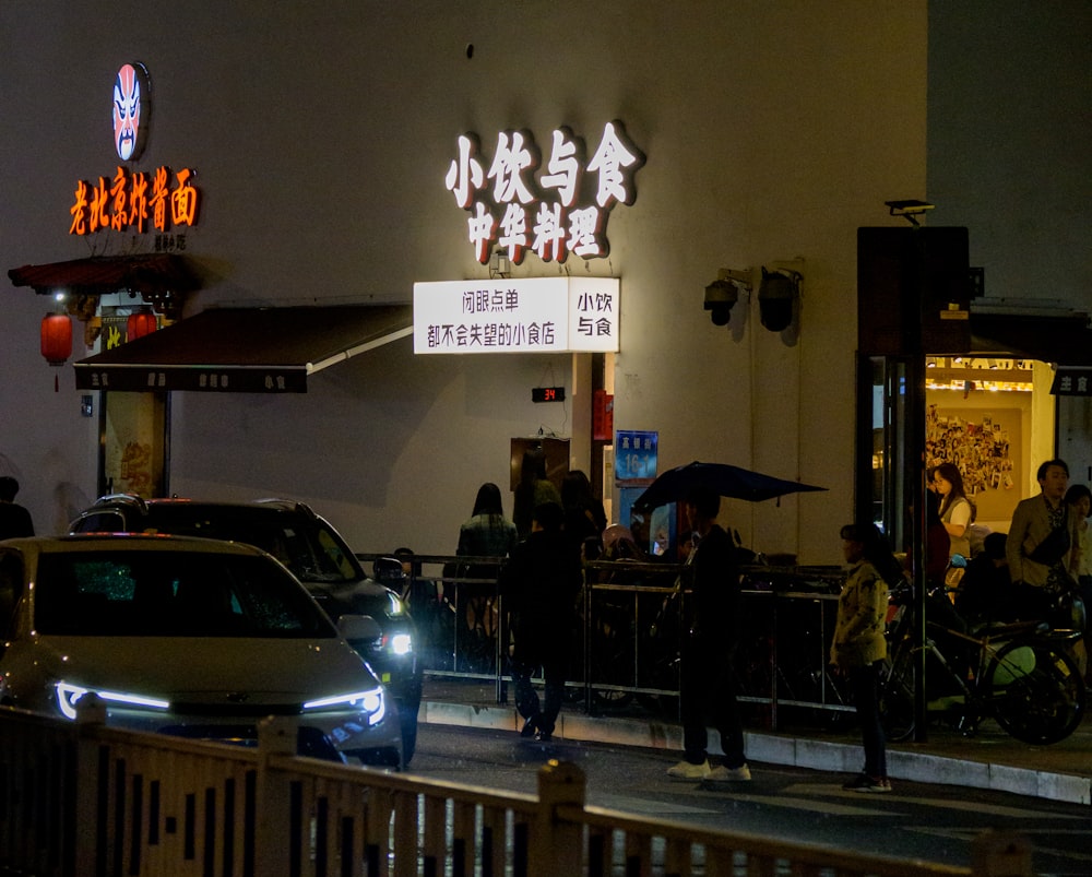 a group of people standing outside of a restaurant at night