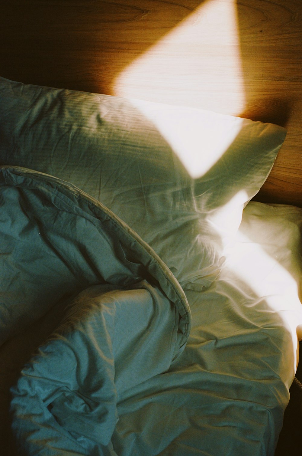 a bed with a white comforter and a wooden head board