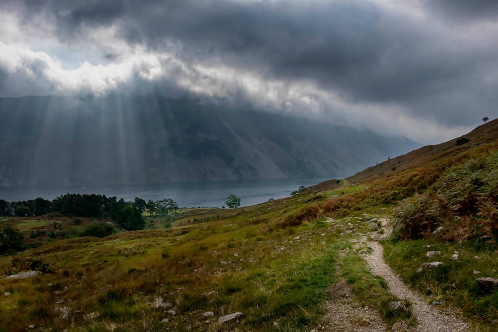 a path leading to a mountain with a lake in the distance