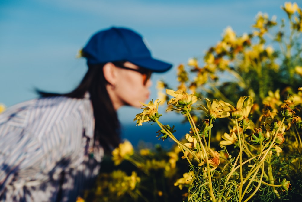 a woman wearing a blue hat standing in a field of yellow flowers