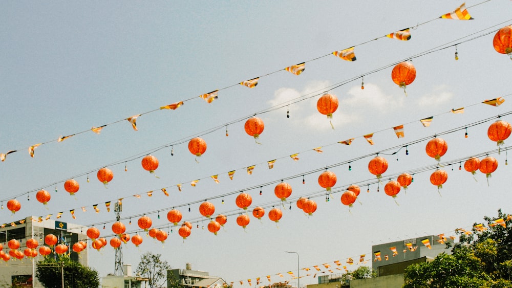 a bunch of orange paper lanterns hanging from a line