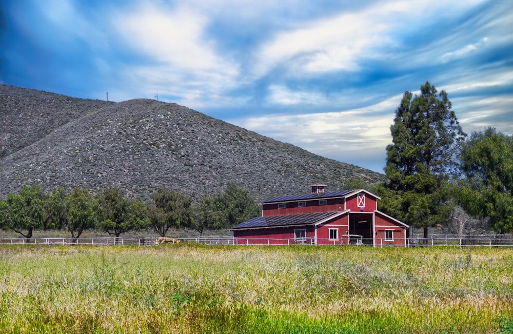 a red barn in a field with a mountain in the background