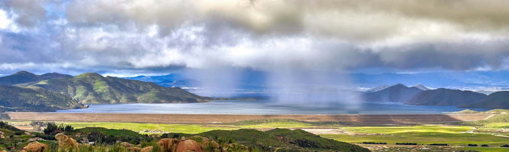 a scenic view of a lake and mountains under a cloudy sky