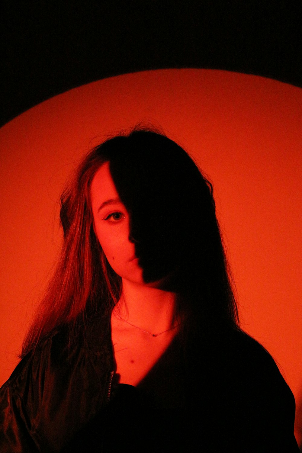 a woman with long hair standing in front of an orange wall
