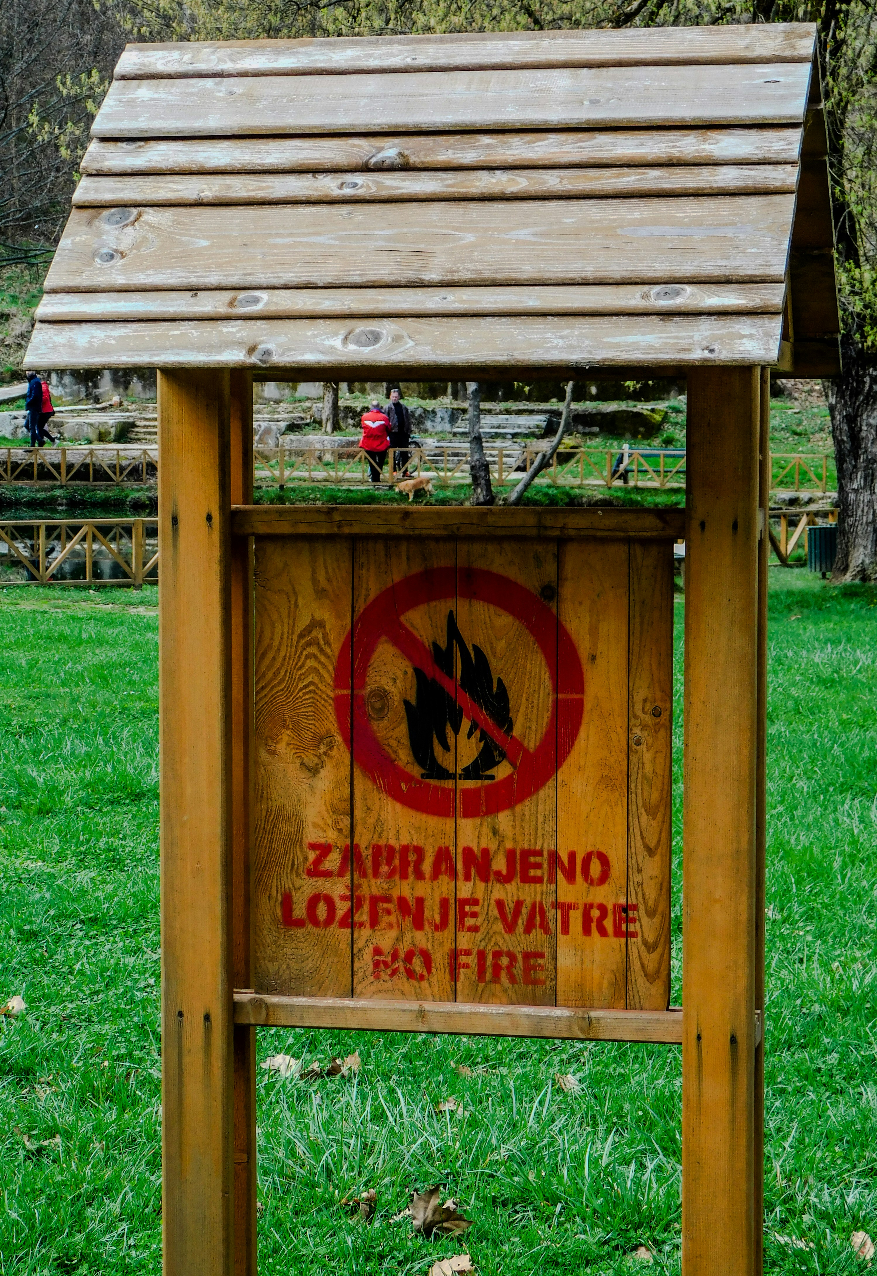 a wooden sign in a grassy area with trees in the background
