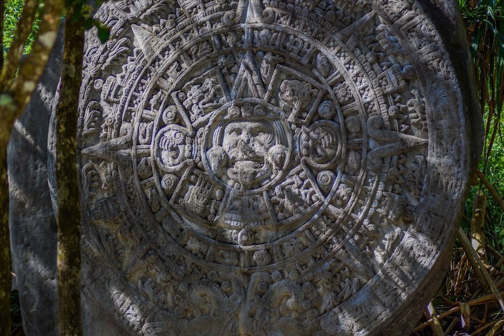 a stone with a design on it sitting in the grass