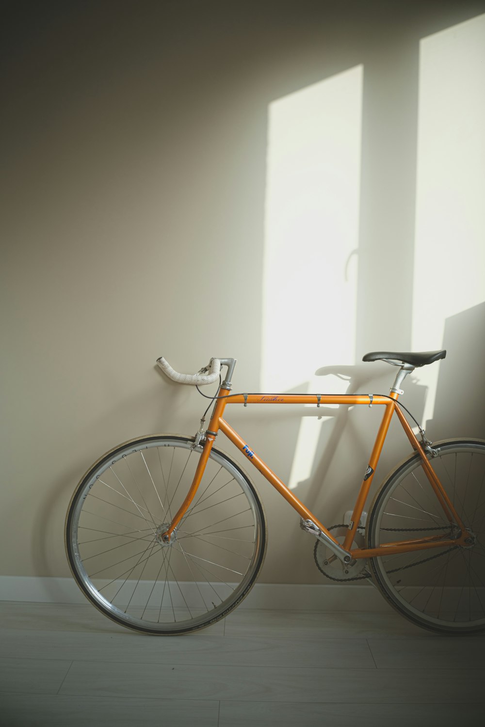 an orange bike leaning against a white wall