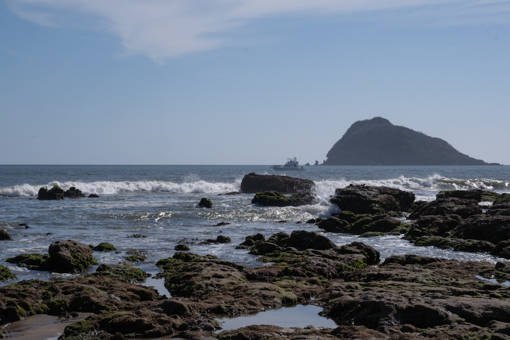 a rock outcropping in the ocean with a boat in the distance