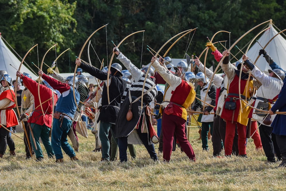 a group of men dressed in medieval clothing holding bows and arrows