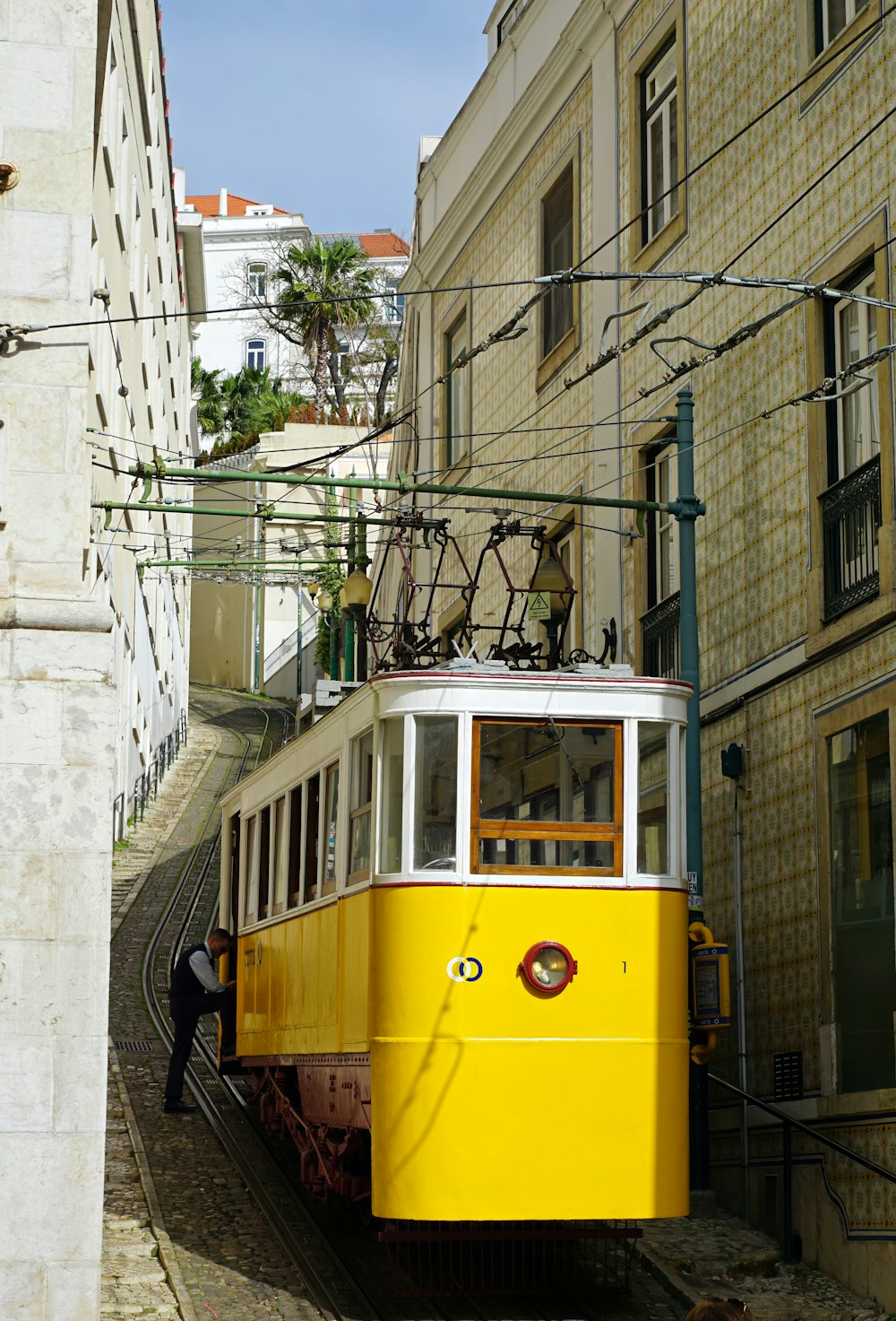 a yellow trolley car on a city street