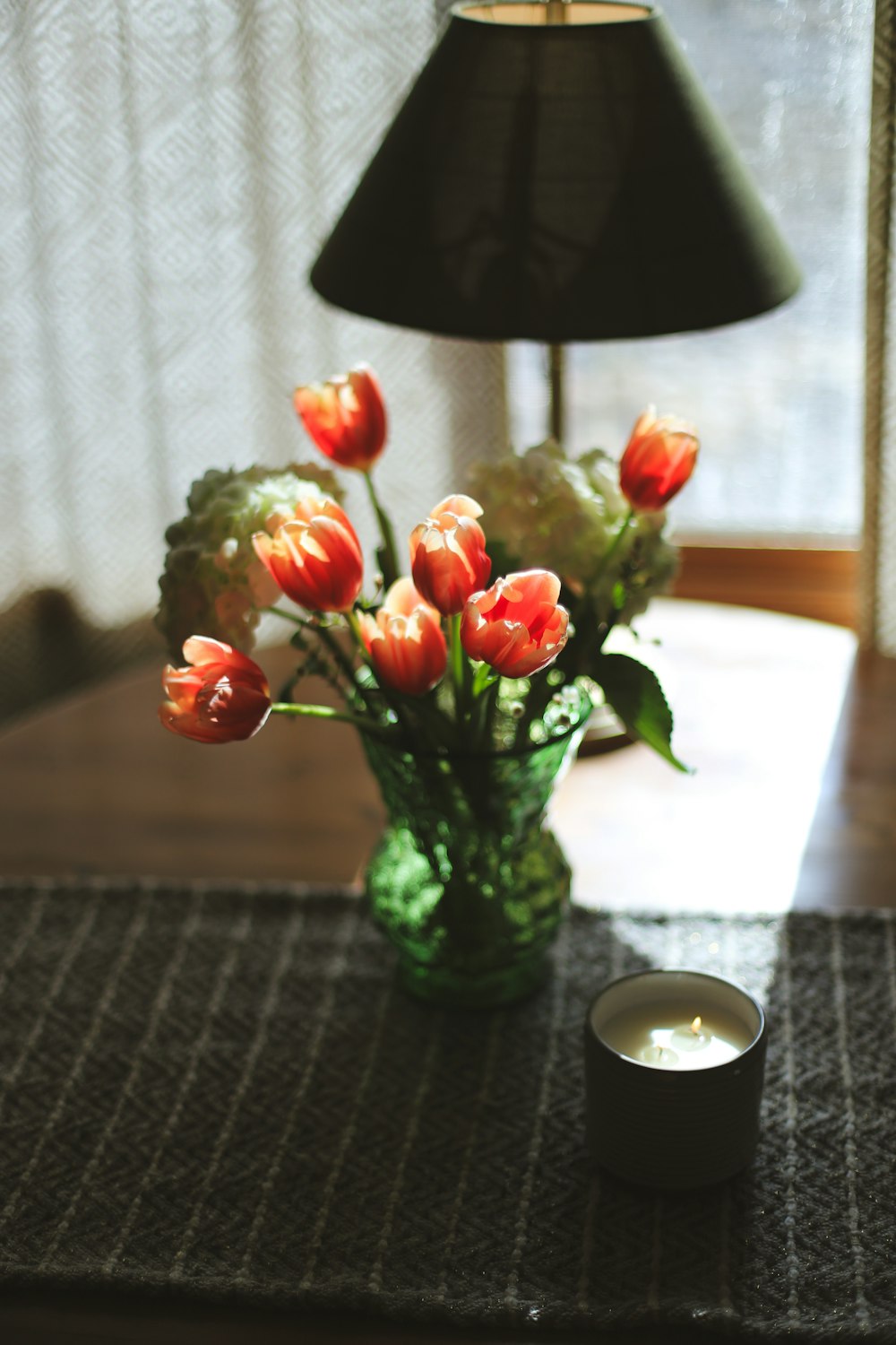 ein Tisch mit einer Vase mit Blumen und einer Kerze darauf