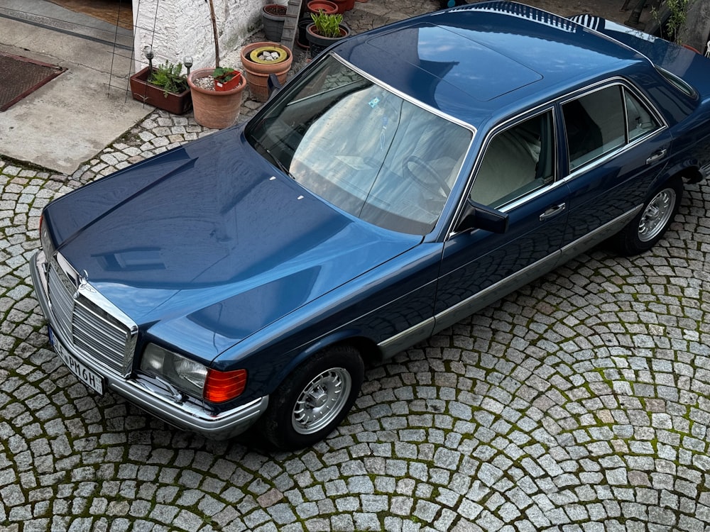 a blue car parked on a cobblestone street