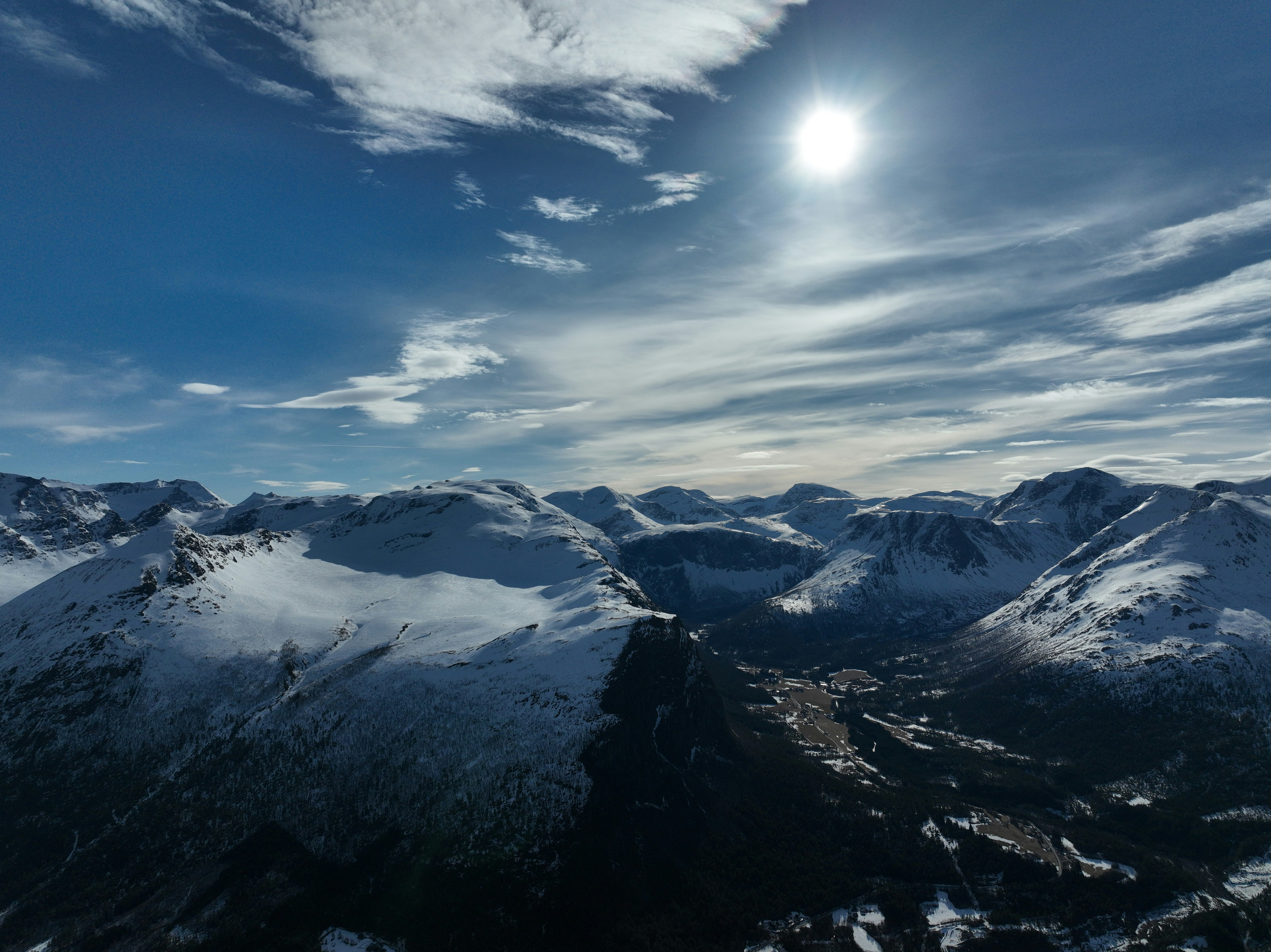 a view of a mountain range with a bright sun in the sky