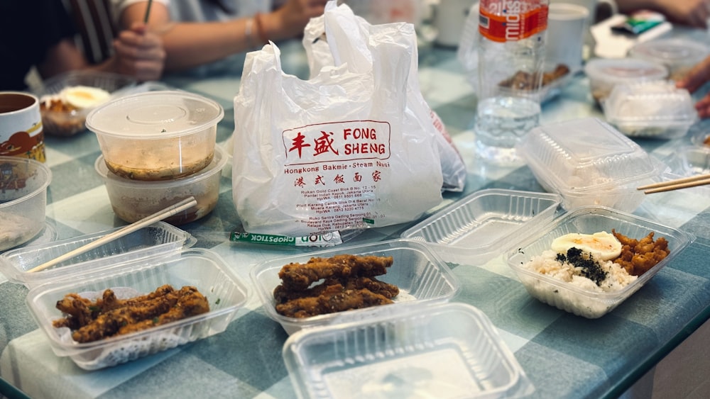 a table topped with plastic containers filled with food