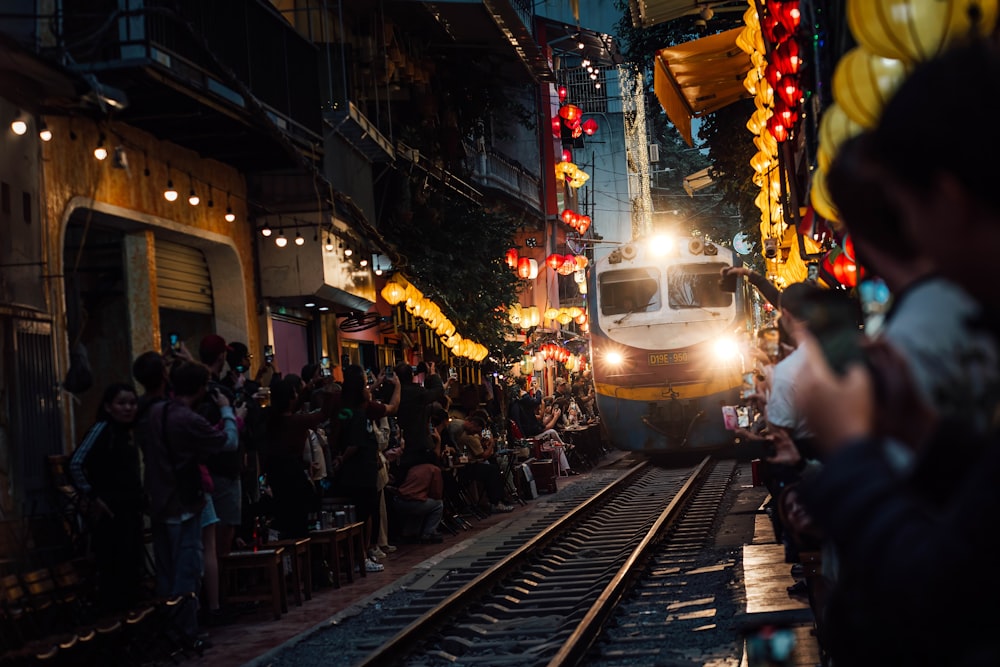 a train traveling down train tracks next to a crowd of people
