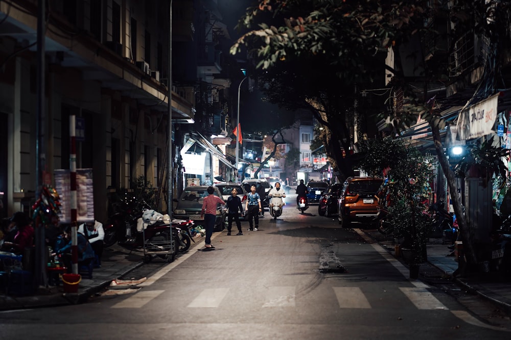 a group of people walking down a street at night