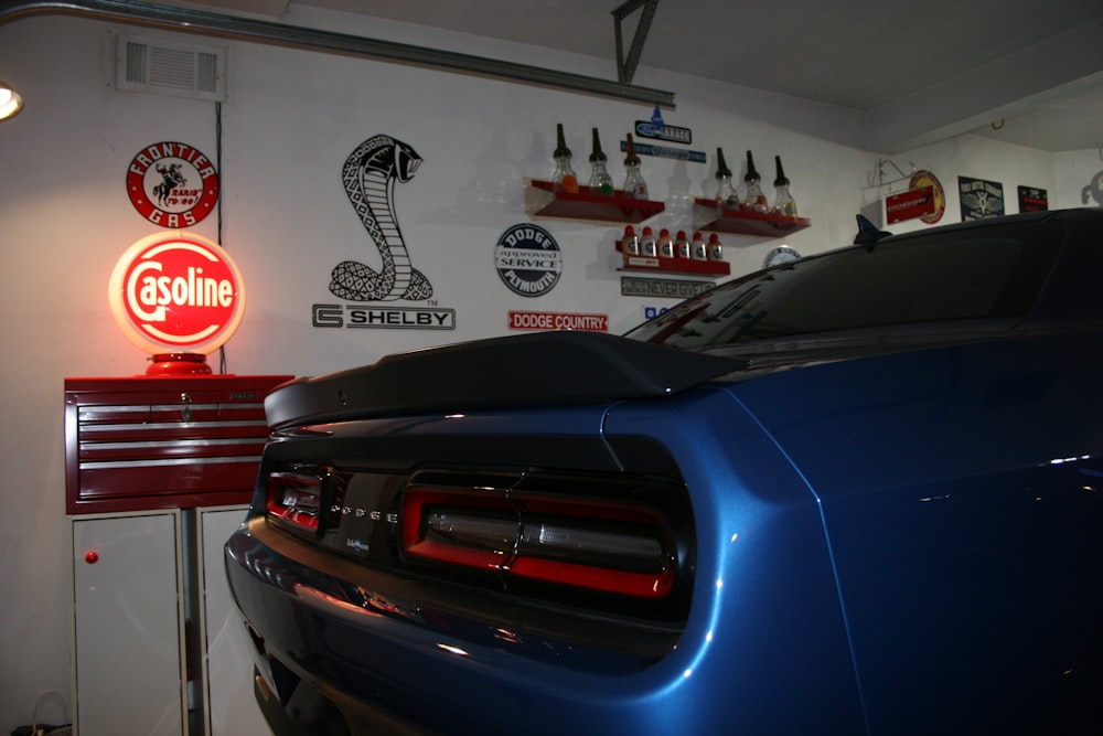 a blue car parked in a garage next to a red sign