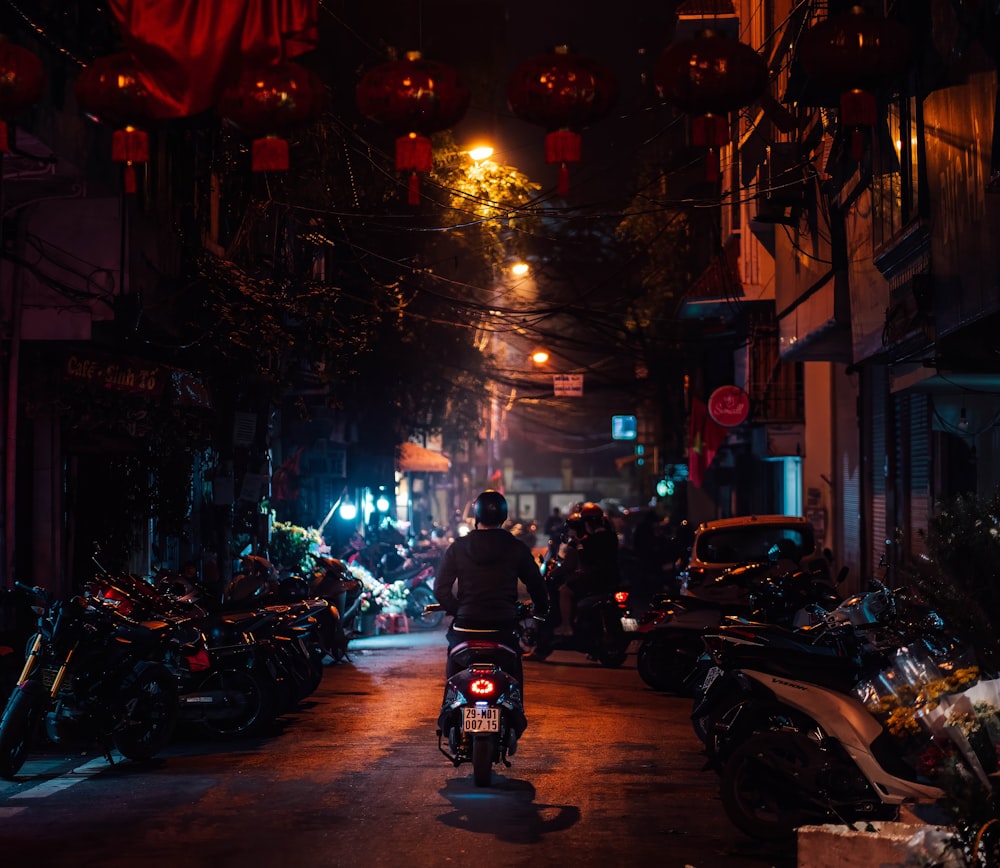 a man riding a motorcycle down a street at night