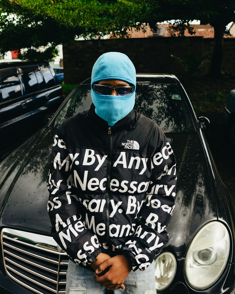 a man in a blue mask standing next to a black car
