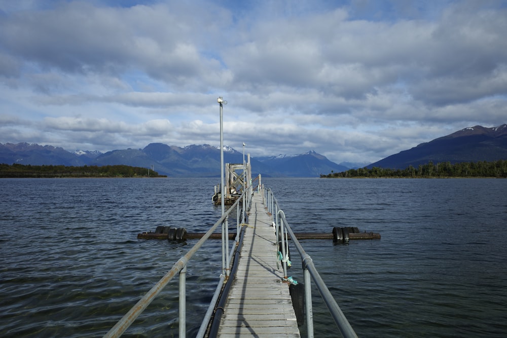 Un muelle en un lago con montañas al fondo