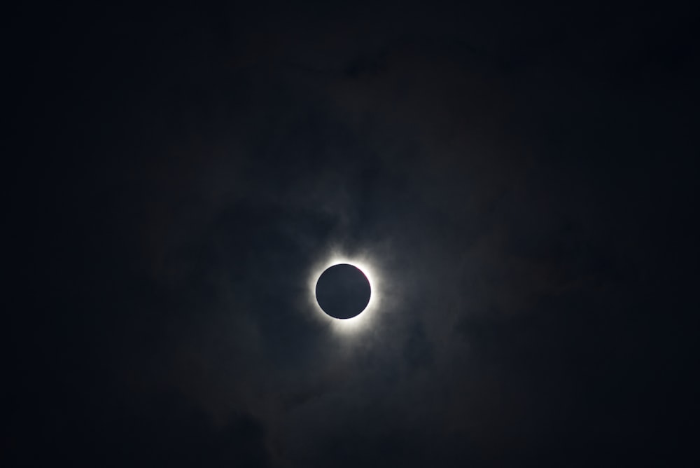 a solar eclipse seen through the clouds in a dark sky