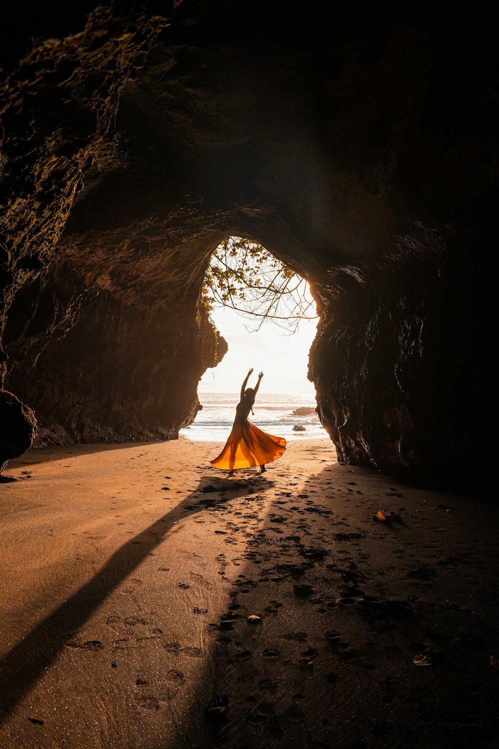 una mujer con un vestido amarillo de pie en una cueva