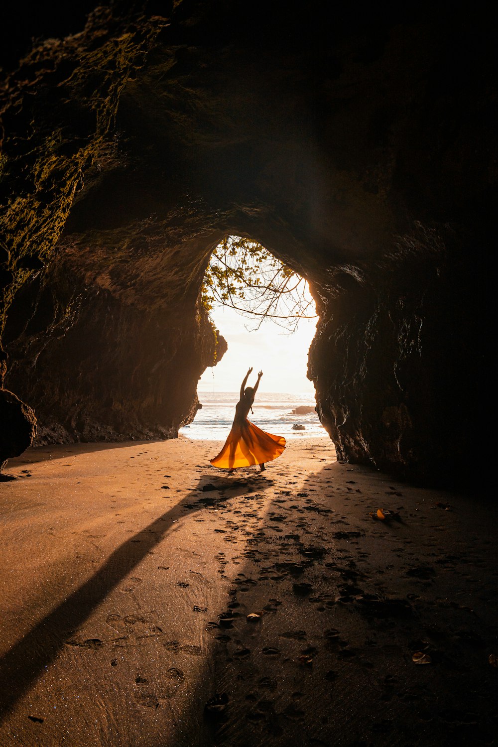 uma mulher em um vestido amarelo em pé em uma caverna