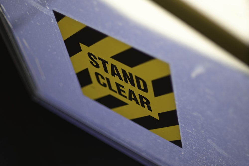 a yellow and black sign that says stand clear