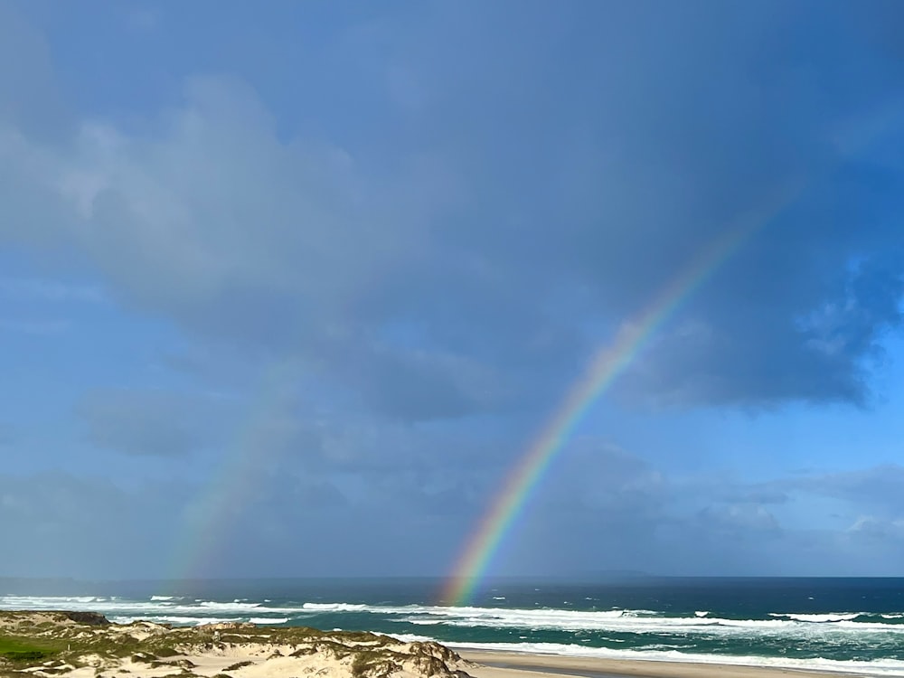 a rainbow in the sky over a beach