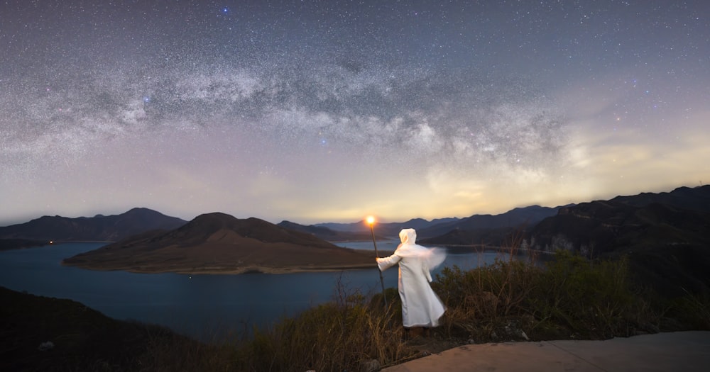 a person standing on top of a hill under a night sky