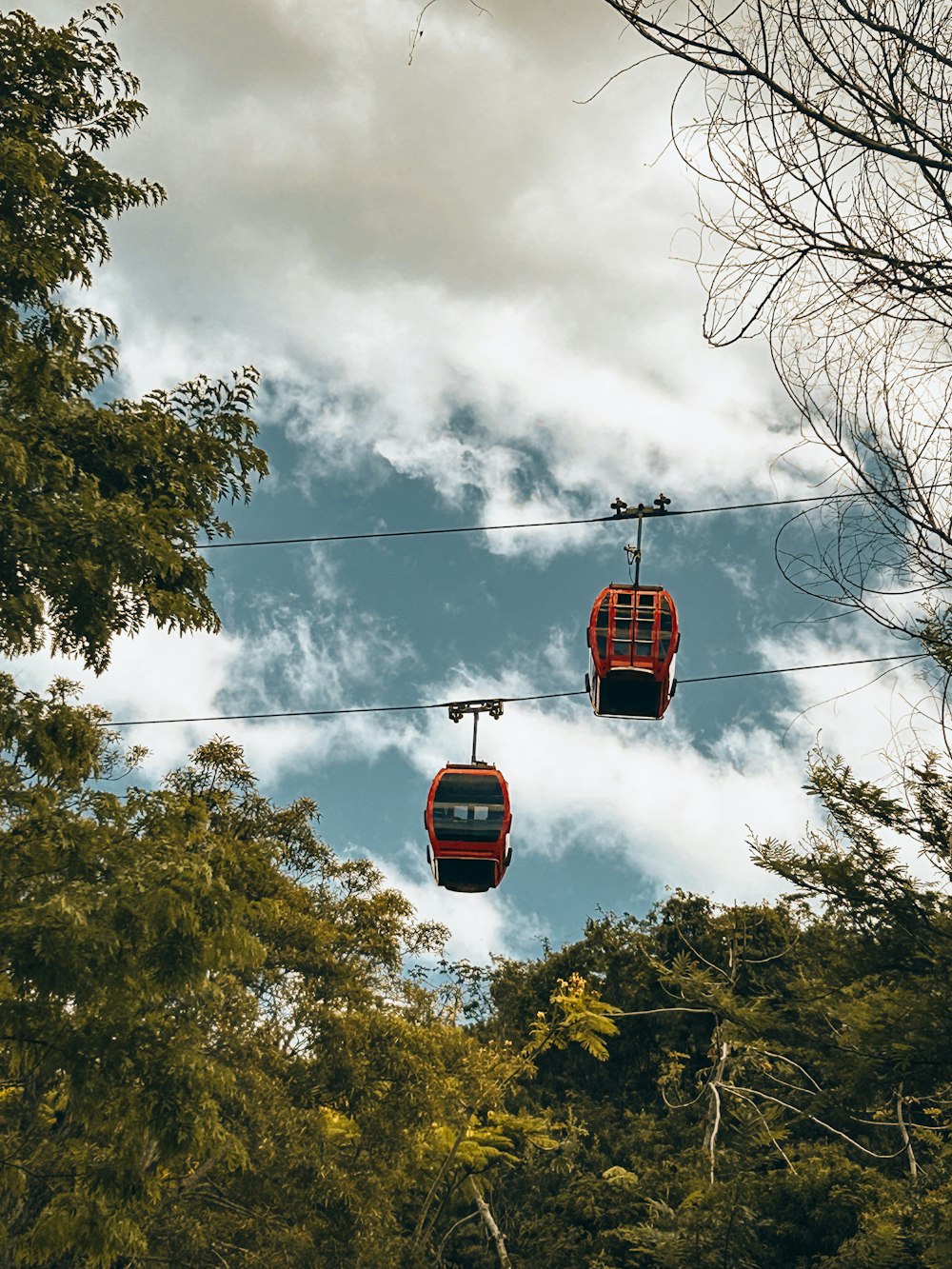 a couple of red gondolas hanging from a wire