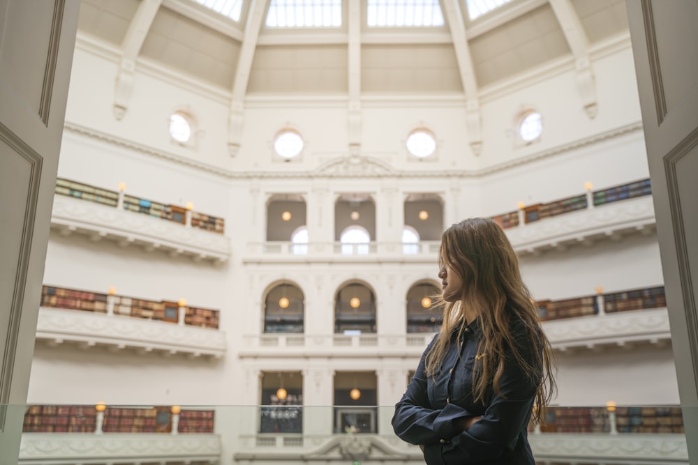 a woman standing in a large building looking up at the ceiling