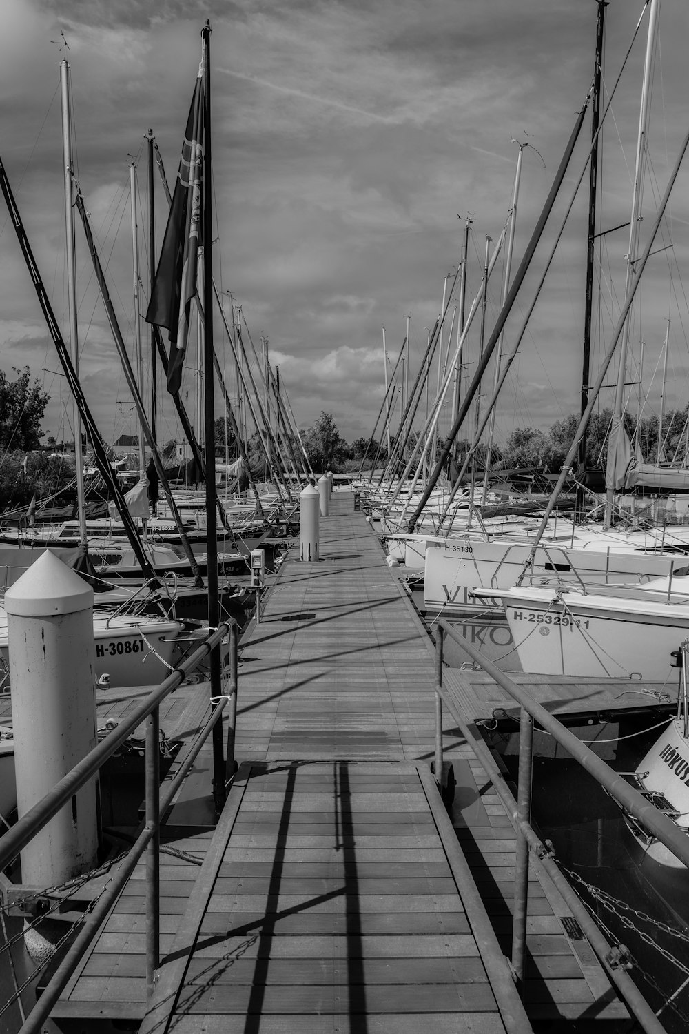 a black and white photo of boats docked at a pier