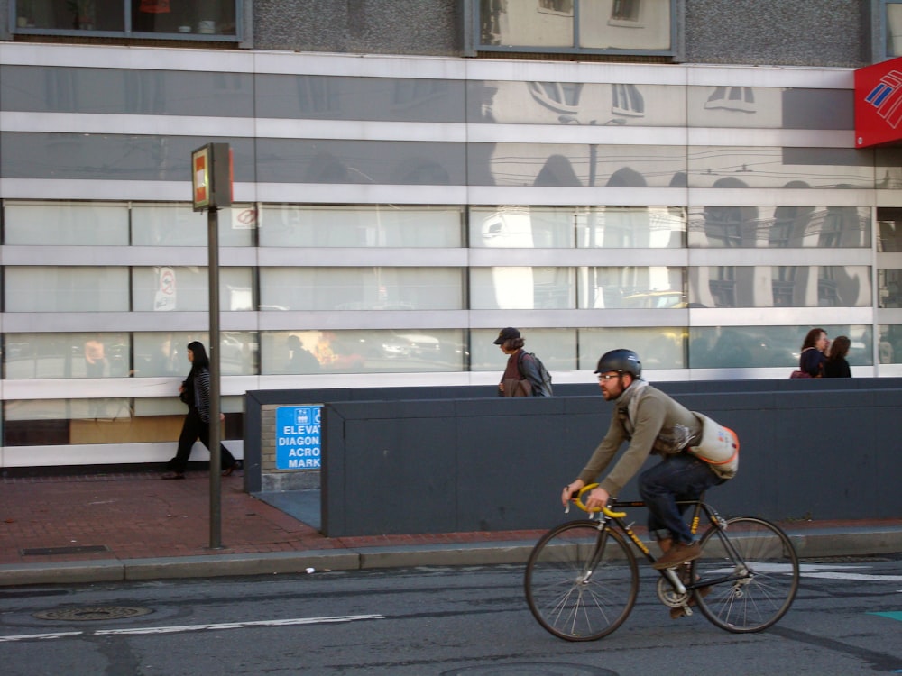 a man riding a bike down a street past a tall building