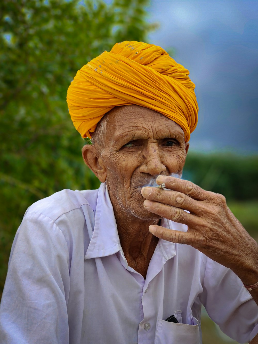 un homme avec un turban jaune fumant une cigarette