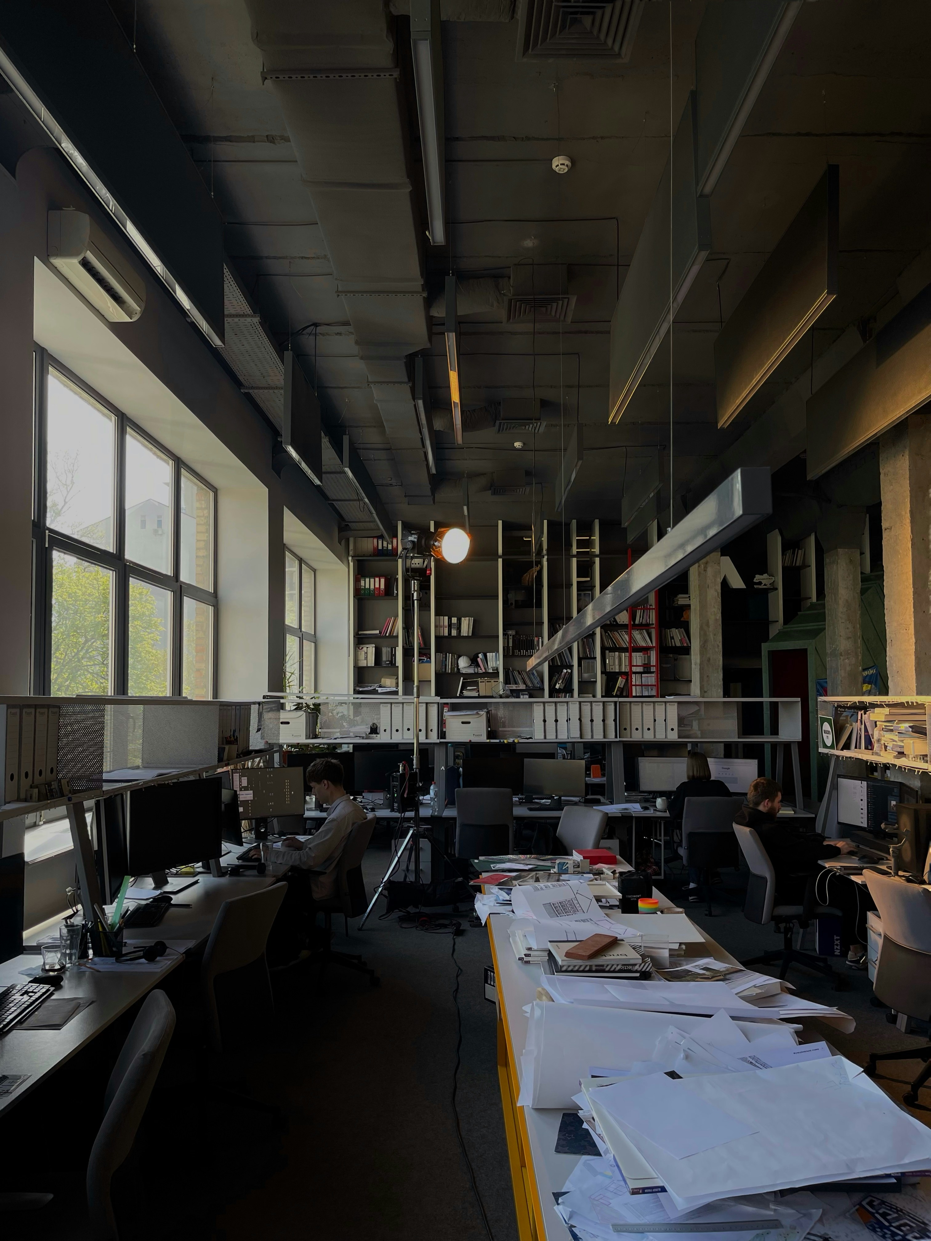 Modern office team working on computers in dim blue-lit open space, dark atmosphere