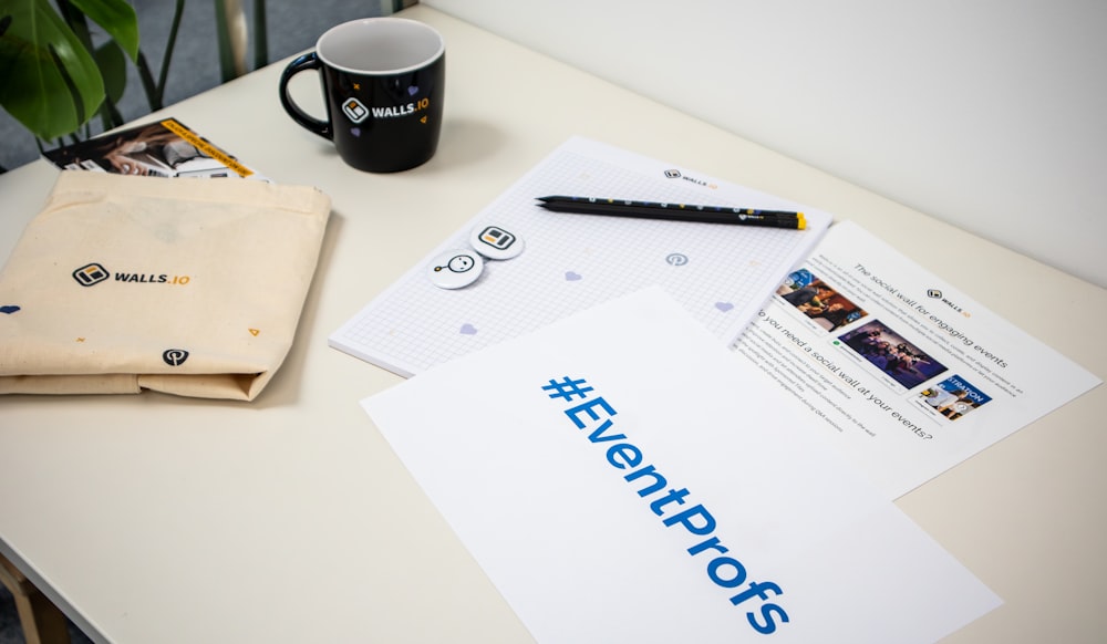 a table with a coffee cup, notepad, pen and envelope