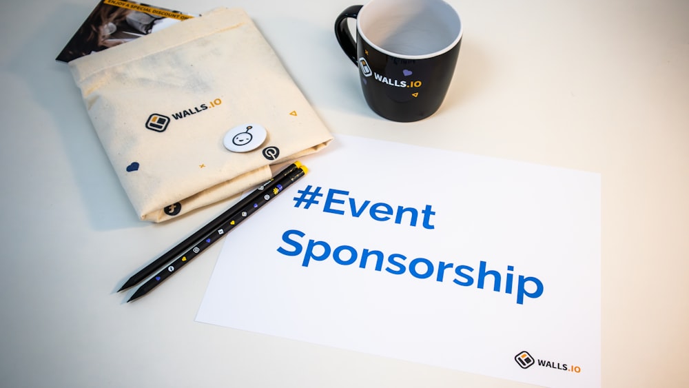 a cup of coffee next to a sign that says event sponsor