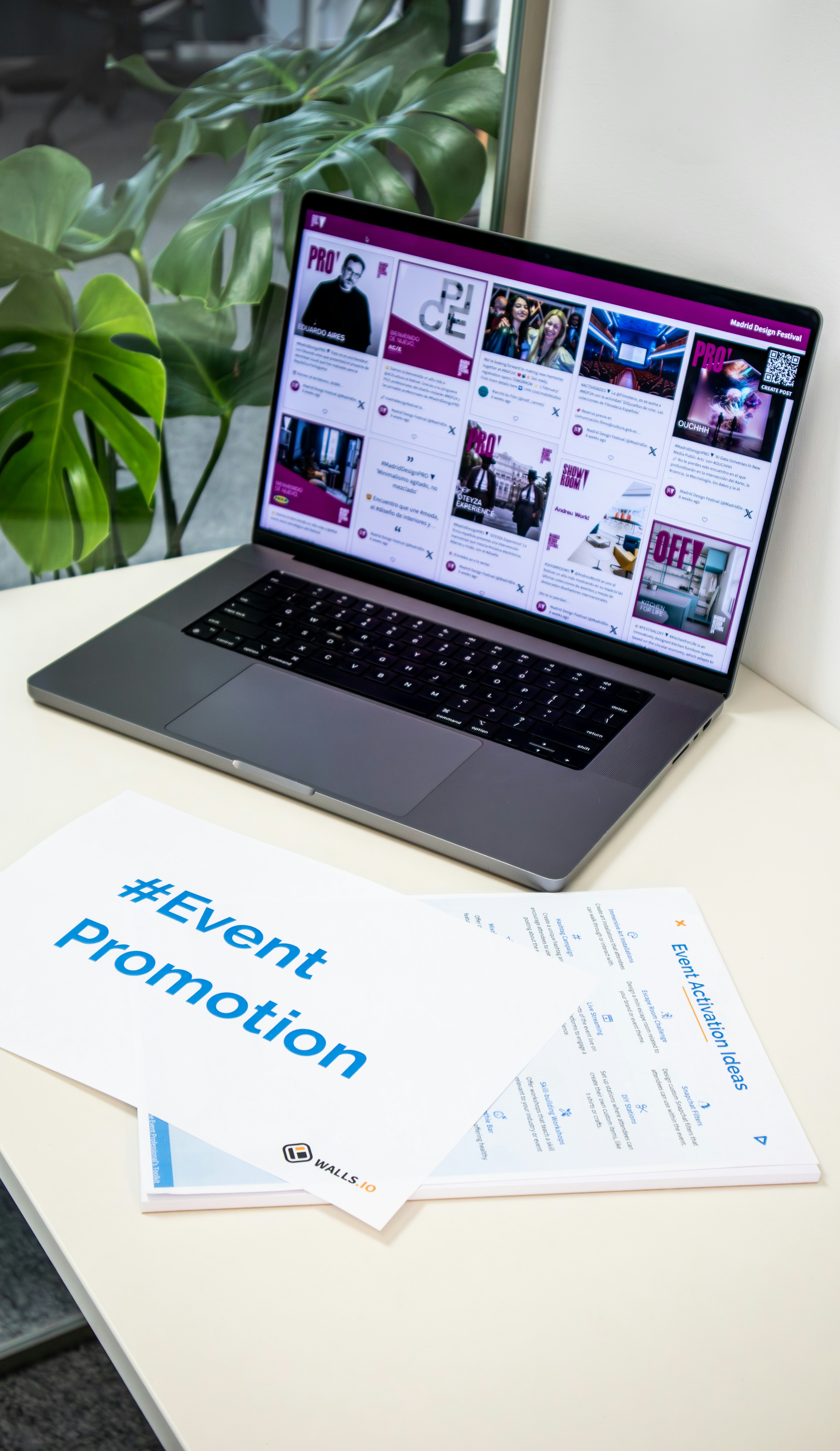 A collection of branded merch and freebies for events with the hashtag #EventPromotion and a laptop showing a social media wall