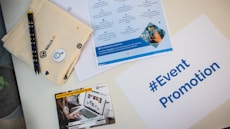 a table topped with a laptop computer next to a brochure