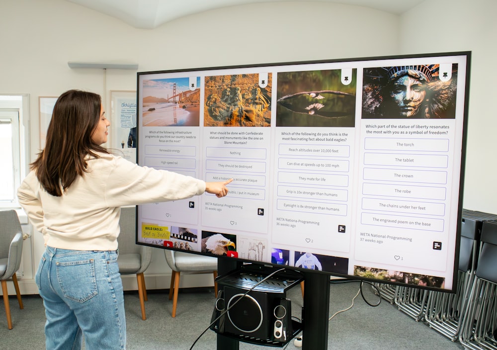 a woman pointing to a poster on a wall