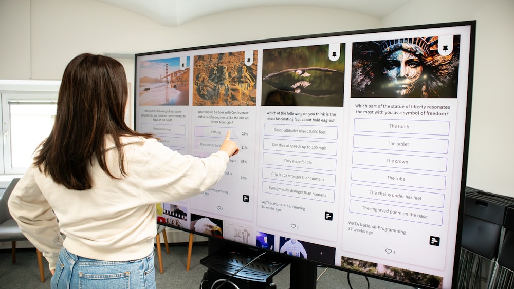 a woman pointing to a poster on a wall