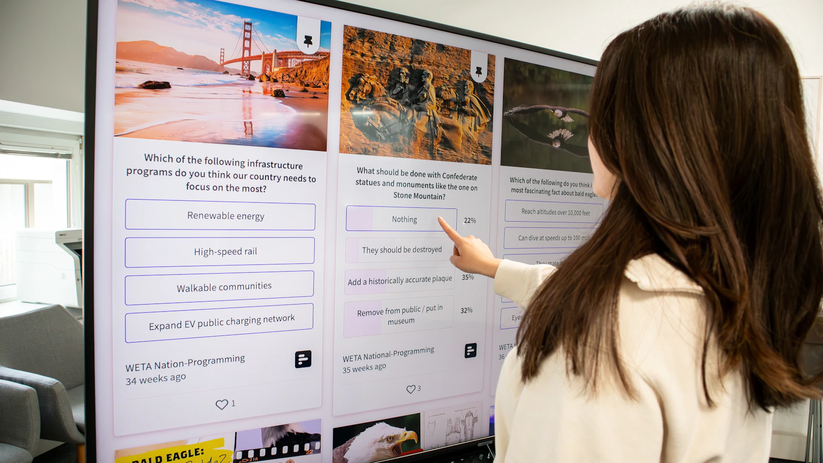 Visitor gesturing toward a large interactive touch wall display