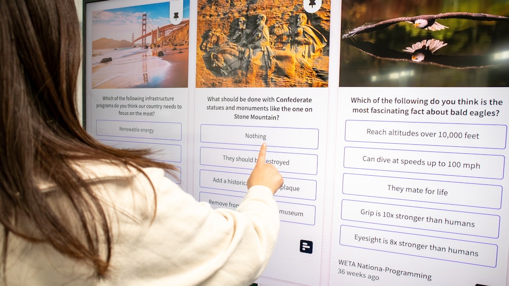 a woman pointing to a poster on a wall