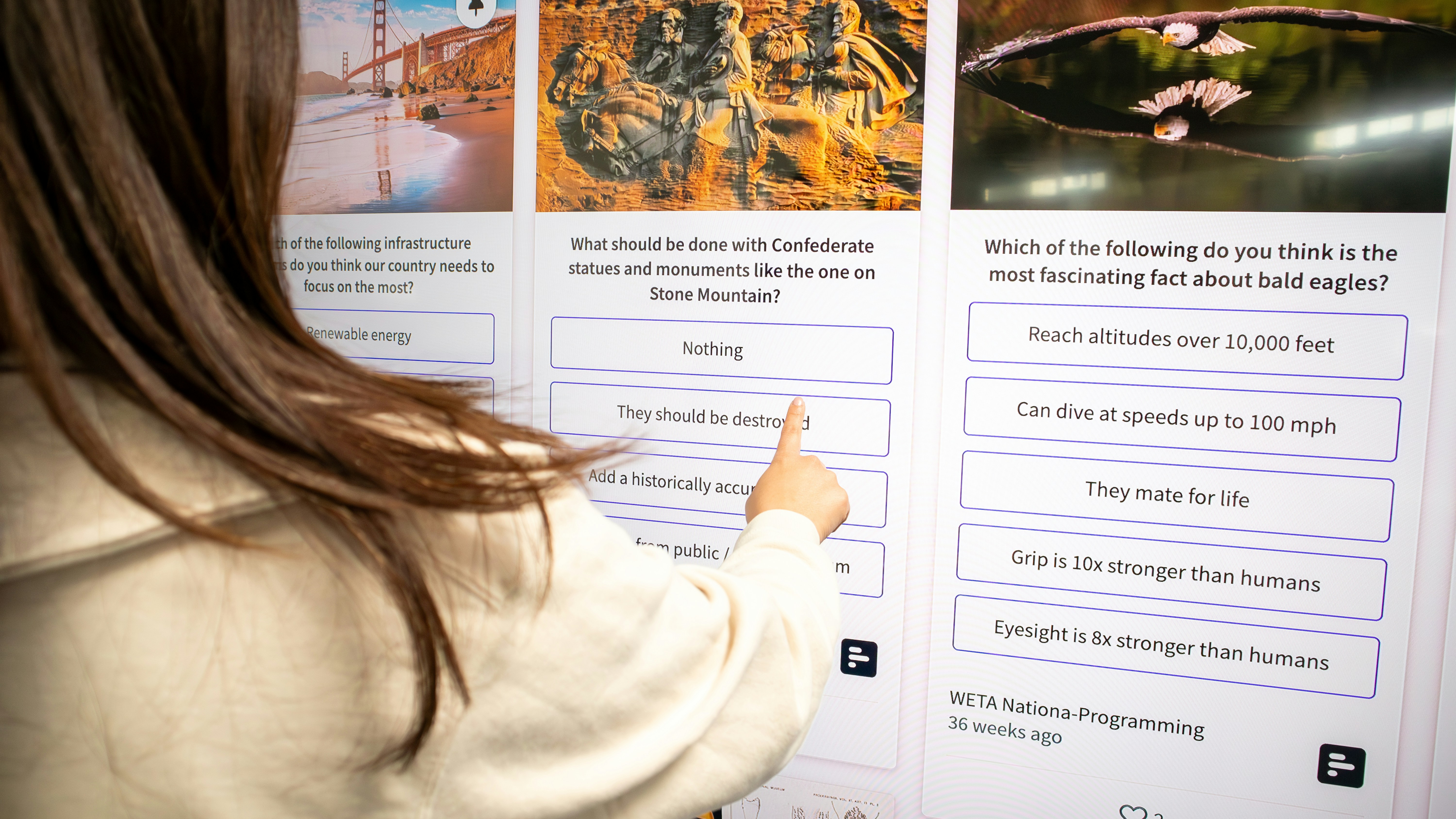 a woman pointing to a poster on a wall