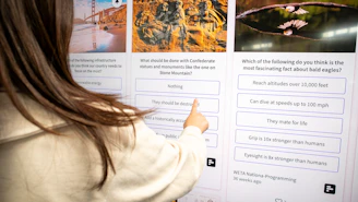 a woman pointing to a poster on a wall