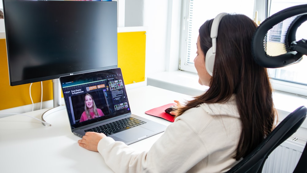 a woman sitting at a desk with a laptop and headphones